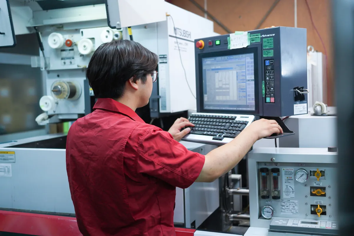 ワイヤー放電加工機を操作する社員