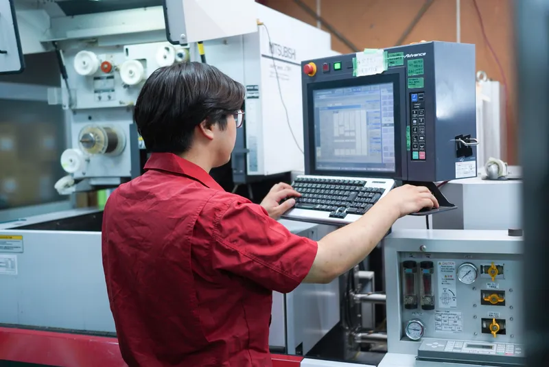 ワイヤー放電加工機を操作する社員